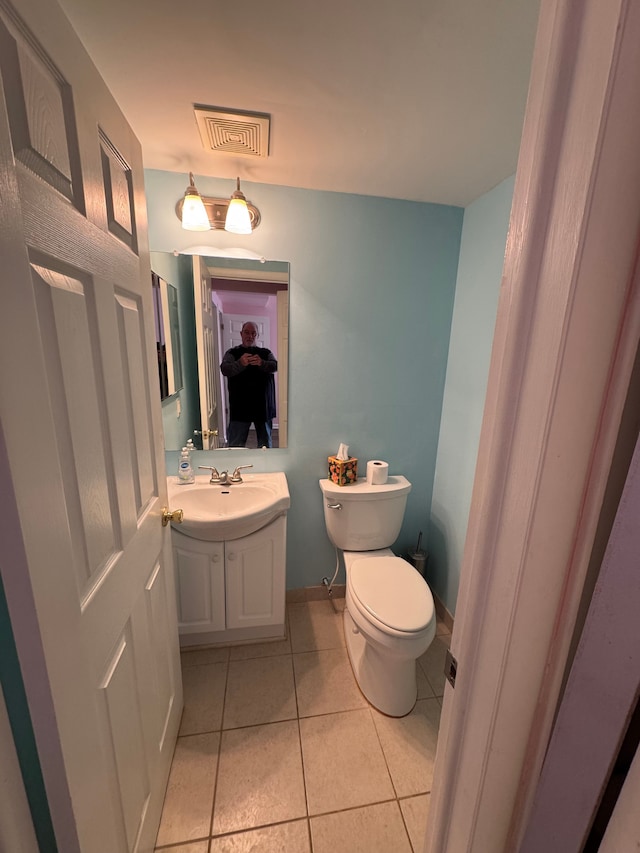 half bath featuring visible vents, toilet, tile patterned flooring, baseboards, and vanity