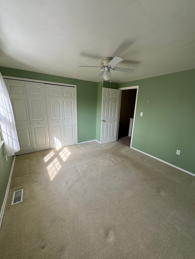 unfurnished bedroom with a ceiling fan, baseboards, visible vents, a closet, and light colored carpet