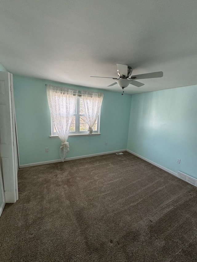 carpeted empty room with visible vents, ceiling fan, and baseboards