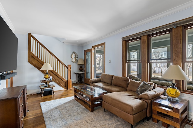 living area featuring a wealth of natural light, wood finished floors, stairs, and crown molding