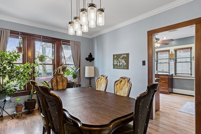 dining room with light wood-type flooring, baseboards, ornamental molding, and a ceiling fan