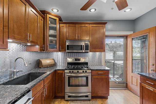 kitchen featuring a sink, dark stone countertops, light wood-style floors, appliances with stainless steel finishes, and ceiling fan