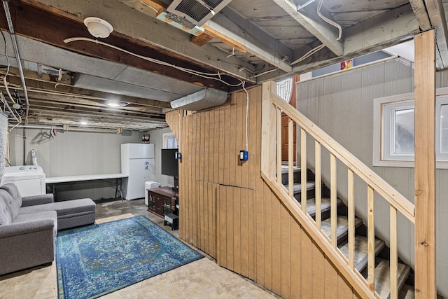 unfinished below grade area featuring stairway, washer / dryer, freestanding refrigerator, and wood walls