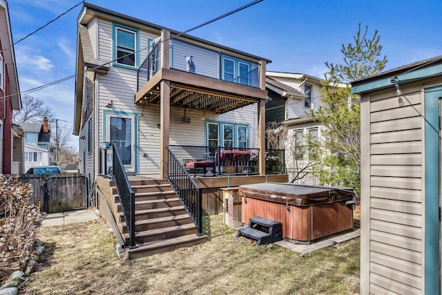 back of house featuring a lawn, a hot tub, and fence