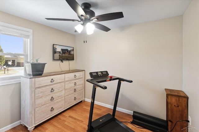 exercise area featuring baseboards, light wood-style floors, and a ceiling fan