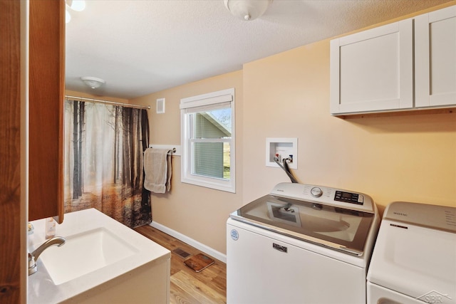 laundry room with visible vents, washer and clothes dryer, a sink, light wood finished floors, and baseboards