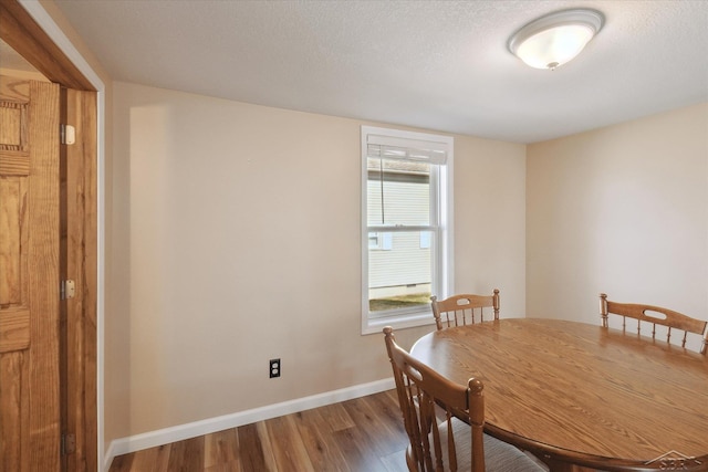 dining space with wood finished floors, baseboards, and a textured ceiling