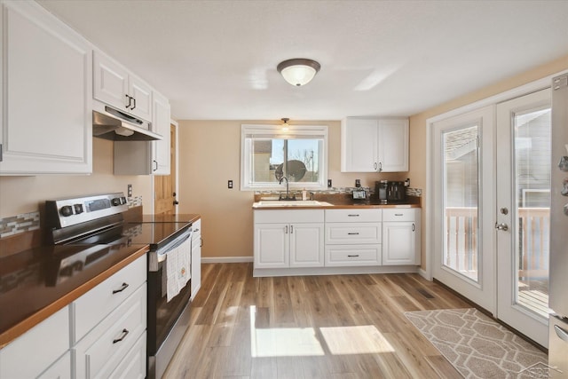 kitchen featuring light wood-style flooring, electric stove, under cabinet range hood, a sink, and white cabinetry