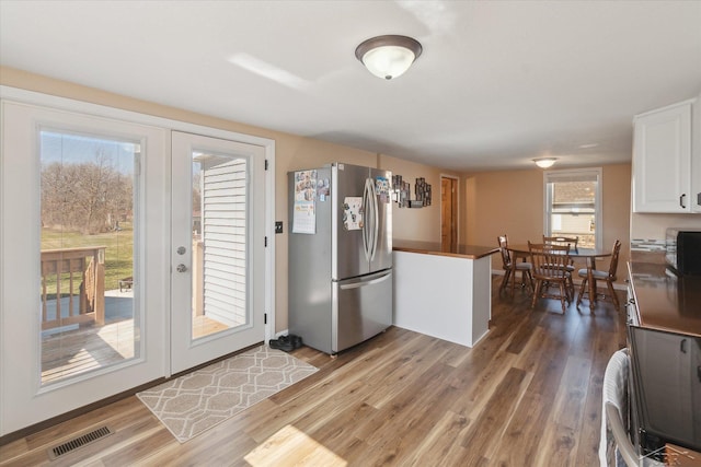 kitchen with white cabinetry, light wood finished floors, visible vents, and freestanding refrigerator