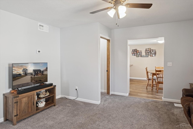 carpeted living room featuring visible vents, baseboards, and a ceiling fan