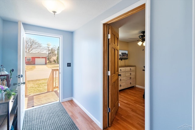 doorway to outside with light wood-type flooring and baseboards