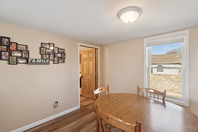 dining room featuring wood finished floors, baseboards, and a textured ceiling