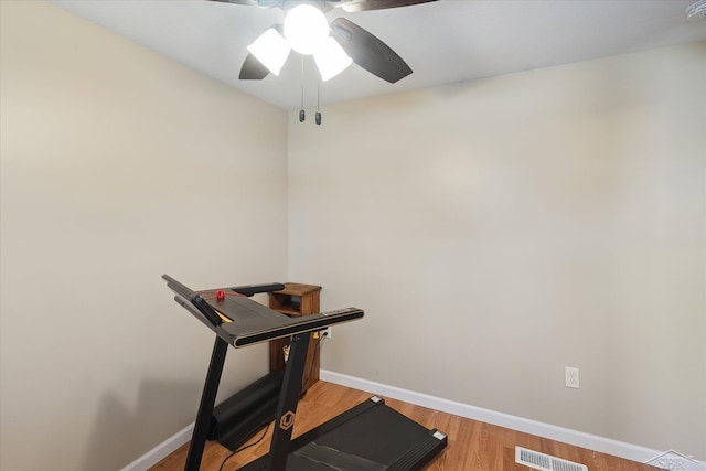 exercise room featuring light wood finished floors, visible vents, a ceiling fan, and baseboards