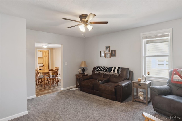 carpeted living room with ceiling fan and baseboards