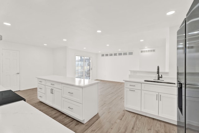 kitchen with a sink, visible vents, light wood-style flooring, and stainless steel refrigerator with ice dispenser