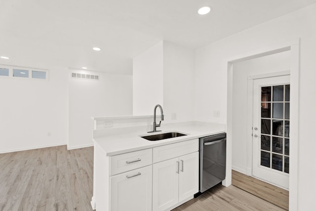 kitchen featuring visible vents, light wood-type flooring, a sink, stainless steel dishwasher, and white cabinets