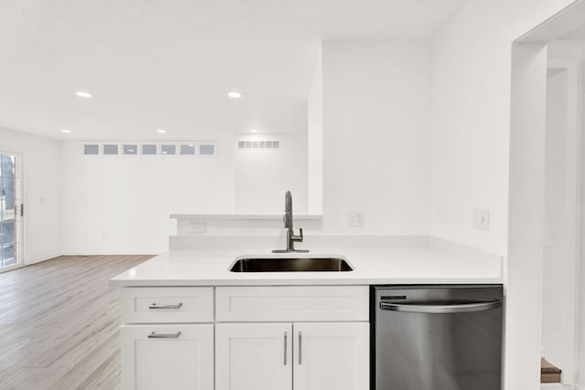 kitchen featuring white cabinetry, light wood-style flooring, a sink, light countertops, and stainless steel dishwasher