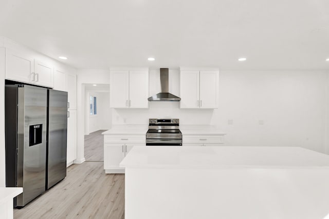 kitchen featuring light wood-type flooring, white cabinetry, appliances with stainless steel finishes, wall chimney exhaust hood, and light countertops