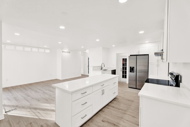 kitchen featuring light countertops, light wood-style floors, stainless steel refrigerator with ice dispenser, under cabinet range hood, and range with electric stovetop