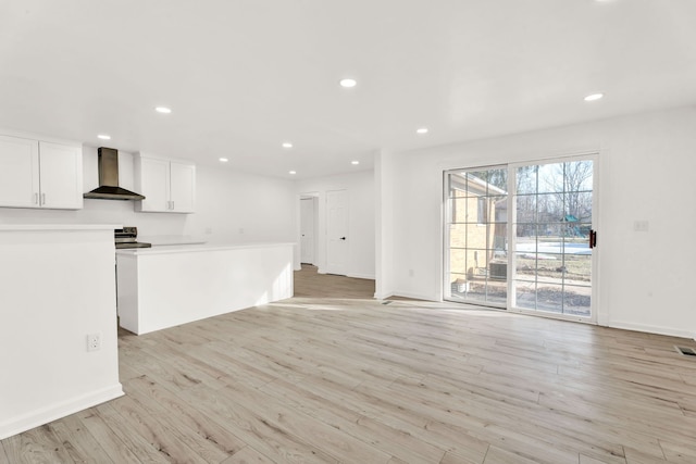 kitchen featuring white cabinets, wall chimney exhaust hood, recessed lighting, and light wood finished floors