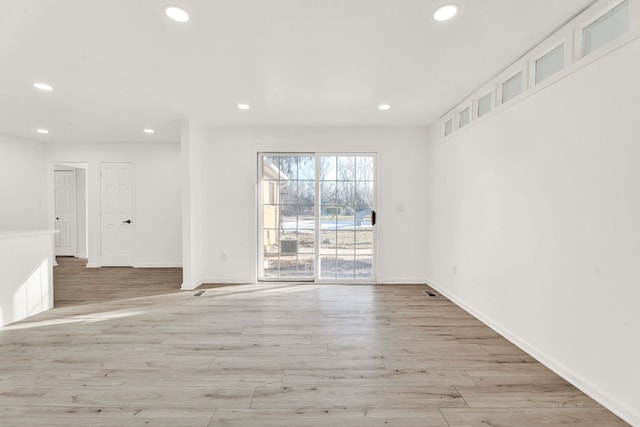 spare room featuring recessed lighting, light wood-type flooring, and baseboards