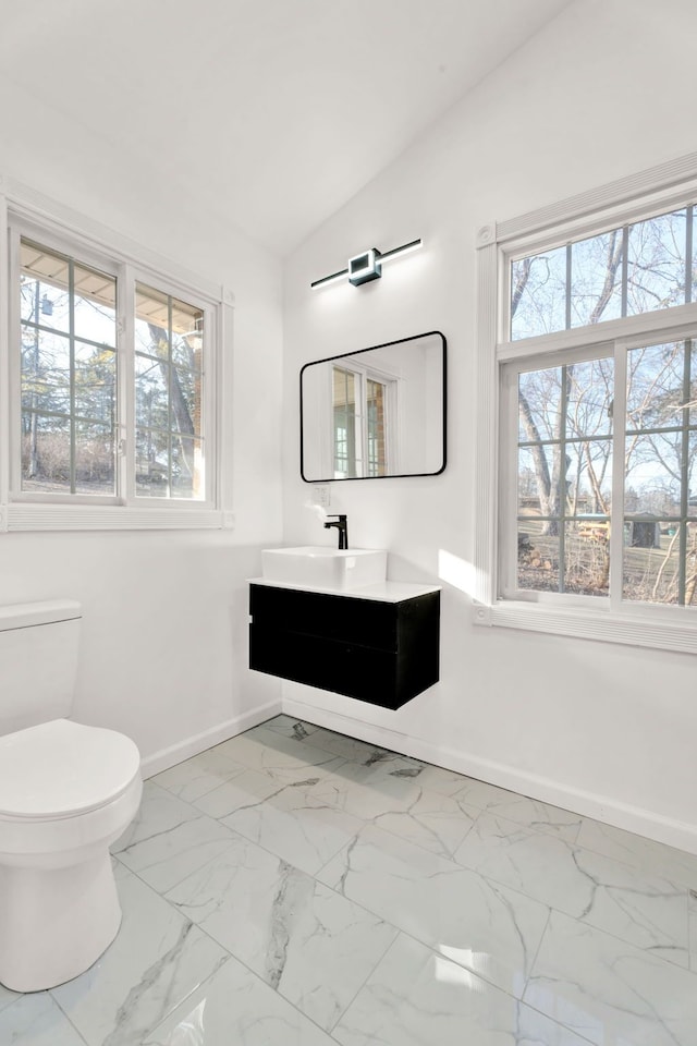 half bathroom featuring baseboards, marble finish floor, a healthy amount of sunlight, and vaulted ceiling