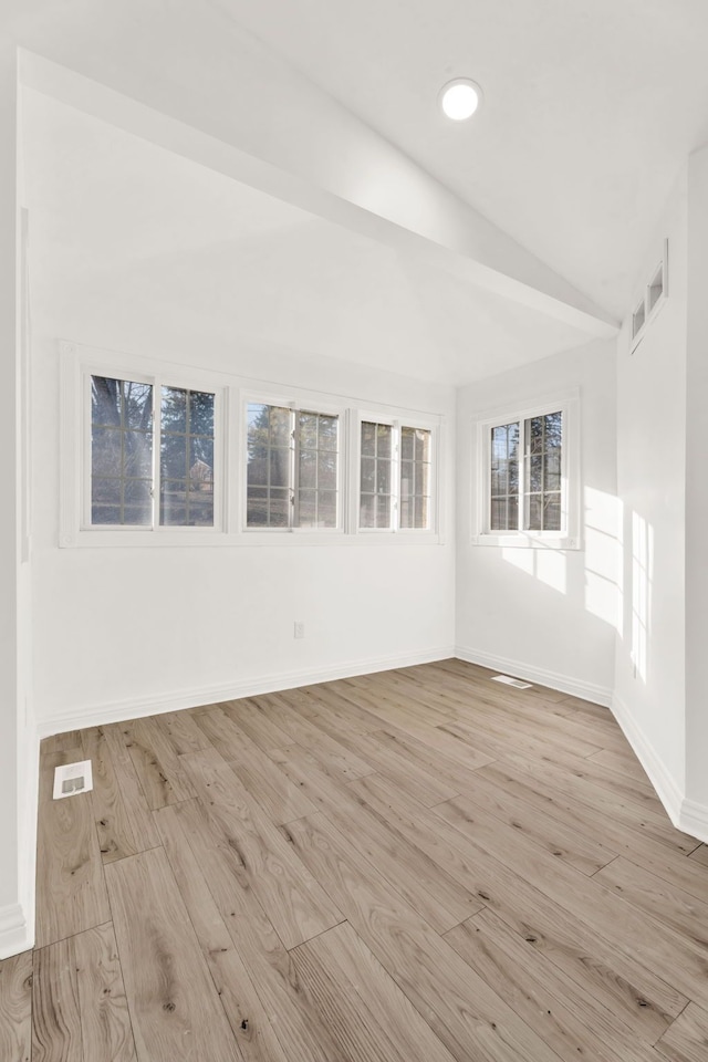 spare room featuring visible vents, light wood-style flooring, baseboards, and vaulted ceiling