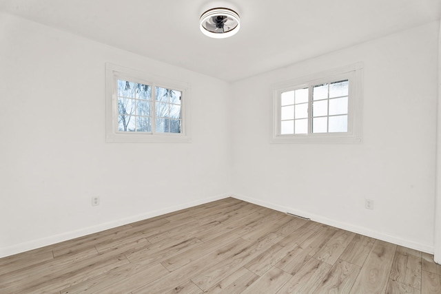 spare room featuring a wealth of natural light, light wood-type flooring, and baseboards