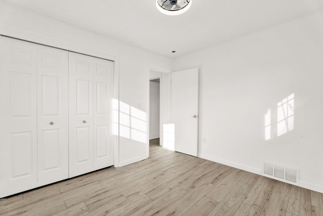 unfurnished bedroom with visible vents, baseboards, light wood-style floors, and a closet