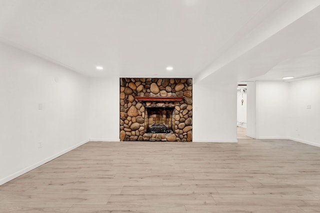 unfurnished living room featuring recessed lighting, a fireplace, baseboards, and light wood-style floors