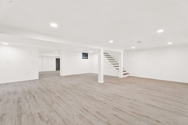 finished basement featuring light wood-type flooring, stairway, baseboards, and recessed lighting