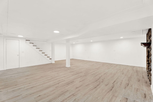 finished basement with stairway, recessed lighting, light wood-type flooring, and baseboards