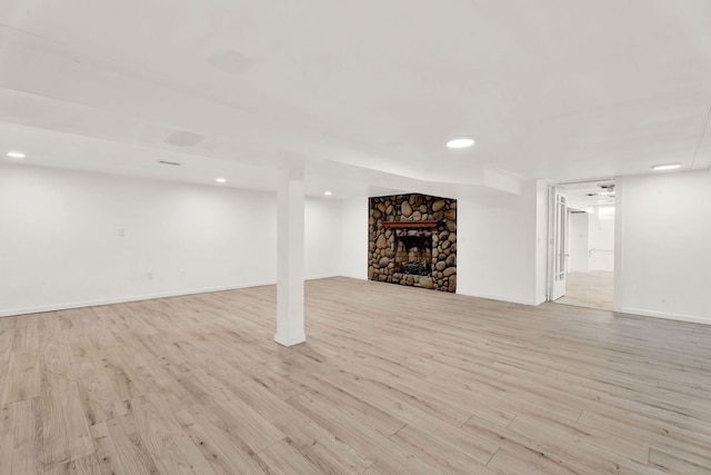 finished below grade area featuring light wood-type flooring, baseboards, and a fireplace