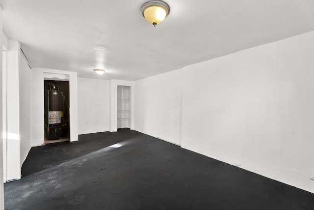 unfurnished room with unfinished concrete flooring and water heater