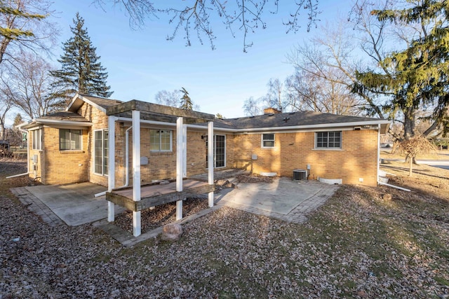 back of house with a patio, brick siding, central AC, and a chimney