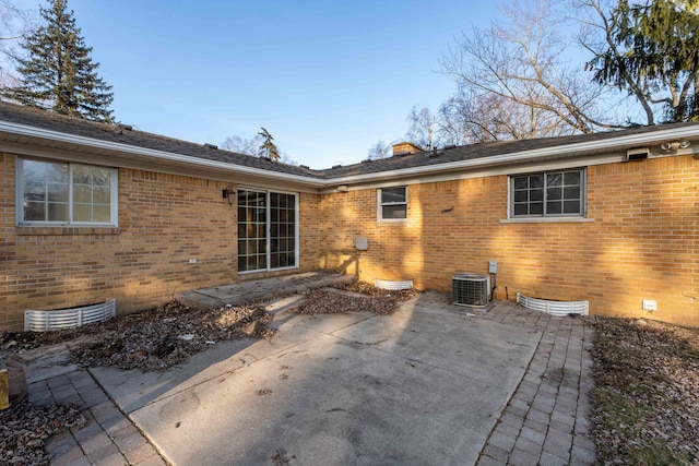 rear view of house featuring a patio area, brick siding, central AC, and crawl space