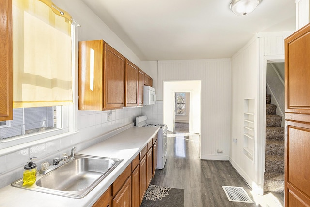 kitchen featuring white appliances, brown cabinetry, visible vents, and a sink