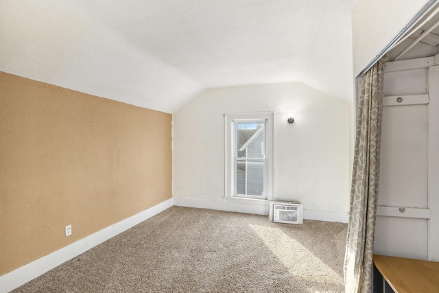 additional living space featuring lofted ceiling, carpet, baseboards, and a wall mounted air conditioner