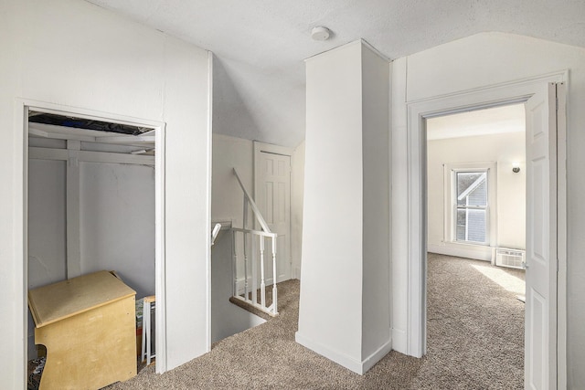 hall with an upstairs landing, carpet flooring, and lofted ceiling