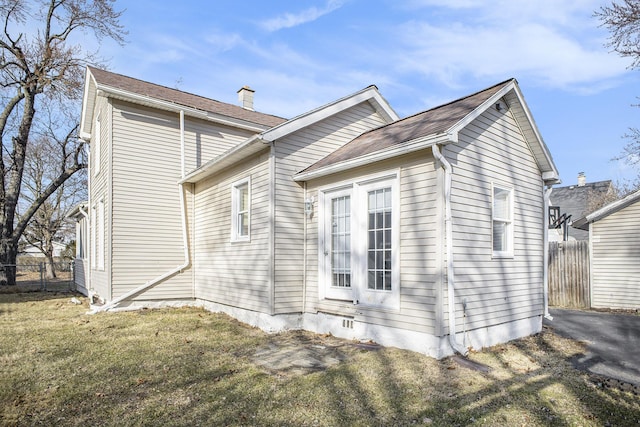 view of home's exterior with a yard, fence, and a chimney