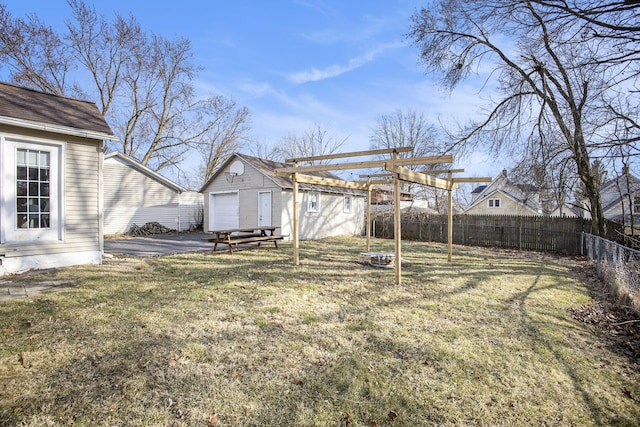 view of yard with aphalt driveway, a fenced backyard, a garage, an outdoor structure, and a pergola