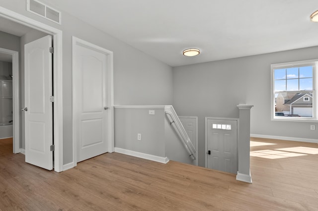 foyer with wood finished floors, visible vents, and baseboards