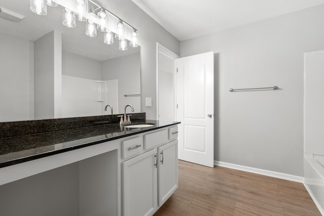 bathroom featuring vanity, wood finished floors, visible vents, baseboards, and a washtub