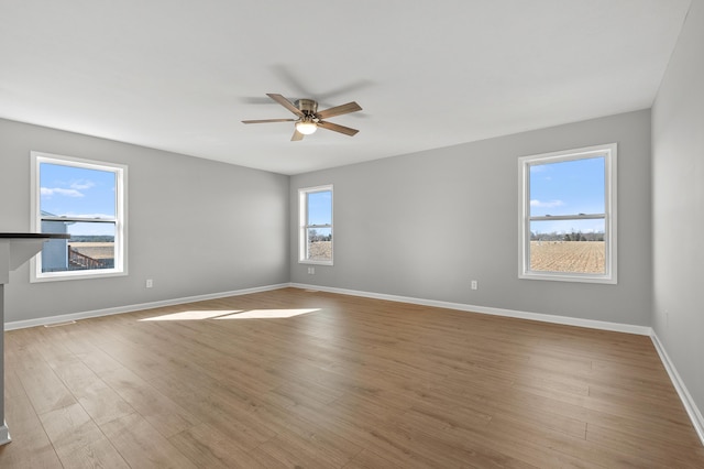 spare room with a ceiling fan, wood finished floors, and baseboards