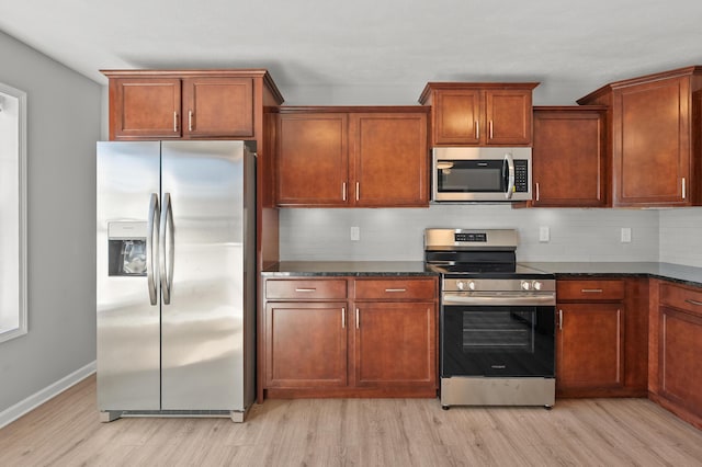 kitchen with light wood-style floors, baseboards, backsplash, and stainless steel appliances