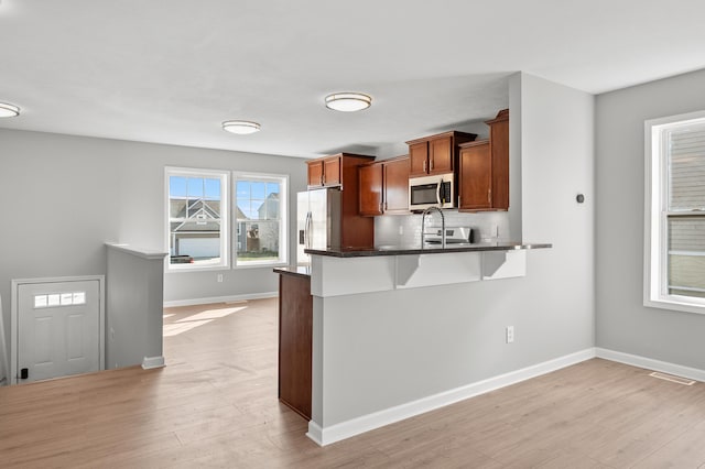 kitchen with dark countertops, visible vents, a breakfast bar, light wood-style flooring, and appliances with stainless steel finishes