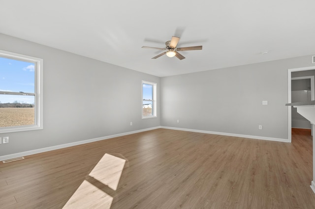 unfurnished room featuring visible vents, ceiling fan, light wood-style floors, and baseboards