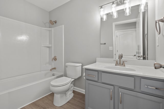 bathroom featuring vanity, wood finished floors, baseboards,  shower combination, and toilet