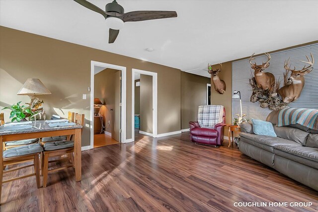 living room with ceiling fan, baseboards, and wood finished floors