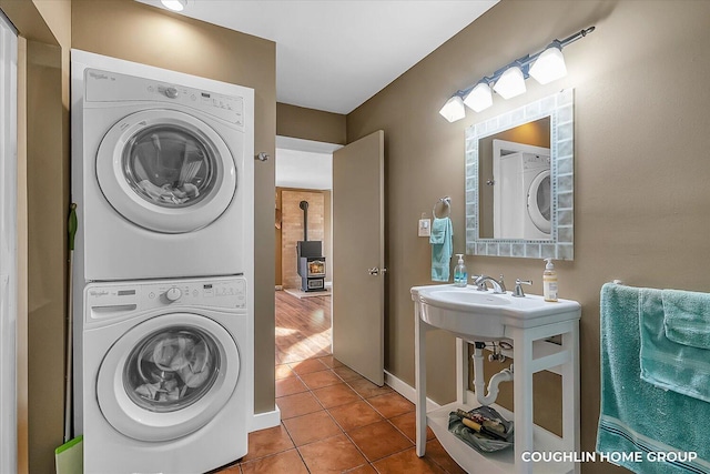 washroom with stacked washer and dryer, laundry area, and tile patterned flooring